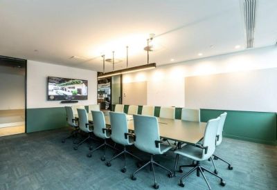 Professional boardroom with a large conference table, teal chairs, and a wall-mounted TV.