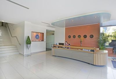 Spacious lobby featuring a wooden reception counter and a white staircase with steel railings.