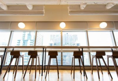 Sleek window-side workspace with a long wooden desk and minimalist bar stools.