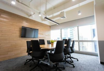 Professional meeting room with a wooden table, black ergonomic chairs, and a wall-mounted TV.