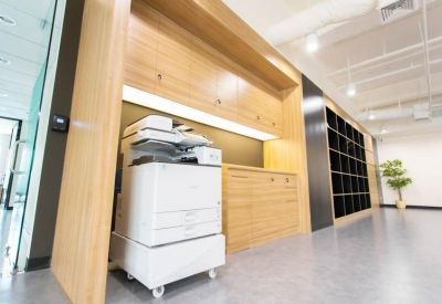 Functional utility area featuring a large white office printer and wooden storage cabinetry.