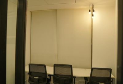 Private office space with three mesh chairs and pendant lighting.