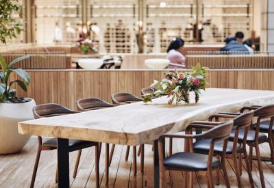 Live-edge wood communal table in a bright dining area with timber cladding.