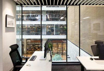 Minimalist workstation with a white desk and view into a glass atrium.