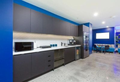 Modern office kitchen with dark cabinetry and white countertops.