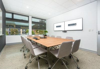 Professional boardroom with a wooden table and dual monitor screens.