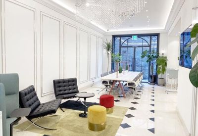 Modern communal lounge with black leather chairs, colorful ottomans, and a long marble table.