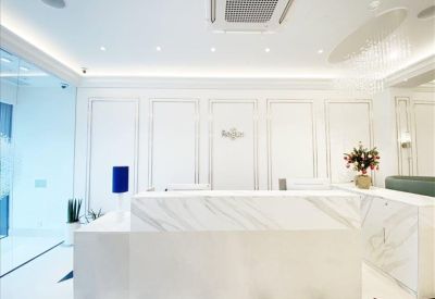Bright white reception area with a marble front desk and classical wall paneling.