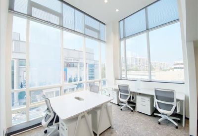 Bright corner office with floor-to-ceiling windows and white desks.
