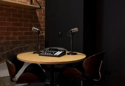 Podcast studio setup with two microphones and a mixing board on a round table.
