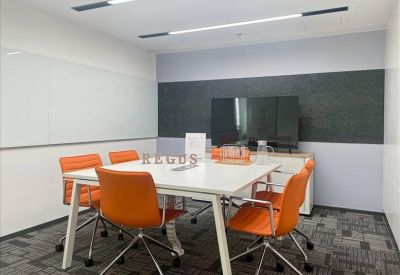 Modern conference room featuring bright orange chairs and a wall-mounted TV.