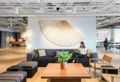 Spacious communal lounge featuring a large decorative wall fan, navy sofas, and wooden flooring.