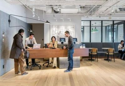Modern reception area with a wooden front desk and a person assisting guests.