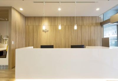 Reception desk with a minimalist white counter and vertical wood-slat feature wall.