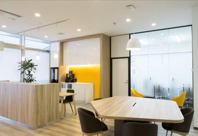 Bright coworking area featuring a large wooden table and yellow accent chairs.