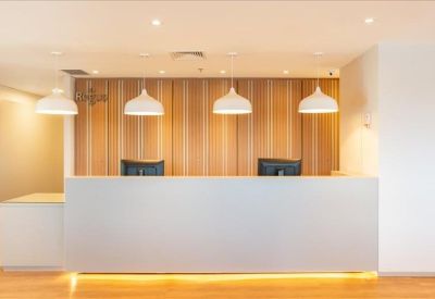 Modern reception desk with warm wood paneling and four white pendant lights.