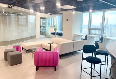 Modern reception lounge with a vibrant pink armchair, white modular sofa, and designer light fixtures.