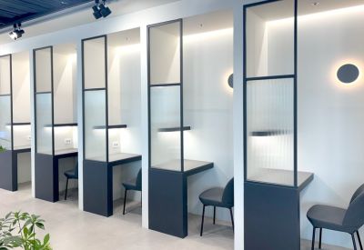 Private semi-enclosed work booths with dark frames and integrated lighting along a white wall.