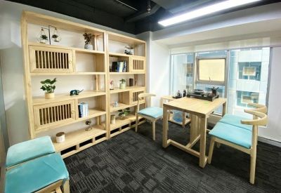 Bright office space featuring a light wood table, bookshelf, and blue cushioned chairs.