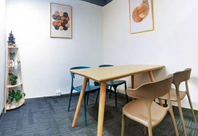 Small meeting room with a wooden table, blue chairs, and framed wall art.