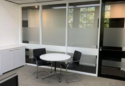 Private office featuring a round white table, black chairs, and frosted glass partitions.