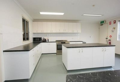 Modern white kitchen with black countertops and a large central island.