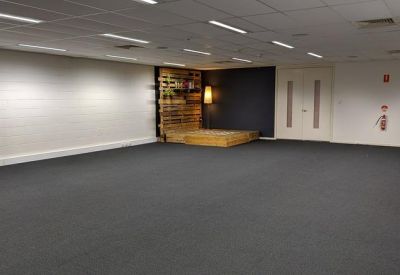 Spacious open-plan office with grey carpet and a wooden pallet stage area.