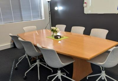 Professional meeting room with a large wooden table and grey ergonomic chairs.