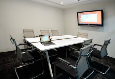 Meeting room with a white conference table, screen, and ergonomic mesh chairs.