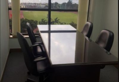 Professional meeting room with a dark wood table and chairs overlooking a city park.