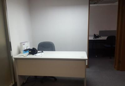 Private office space with a white desk and view of an adjacent workspace.