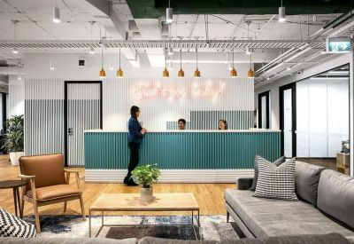 Modern reception area with a teal slatted front desk and comfortable seating.