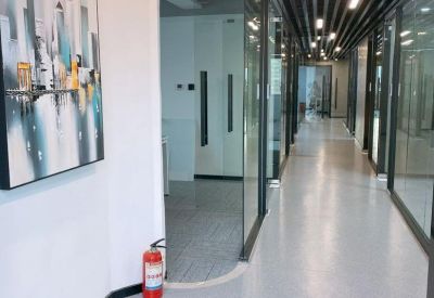 Modern hallway corridor with glass office walls and a colorful city painting.