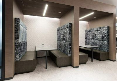 Modern semi-private booths with patterned sound-absorbing panels and white tables.