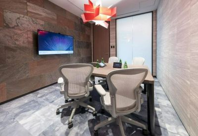 Small meeting room with a wooden table, ergonomic chairs, and a red geometric light fixture.