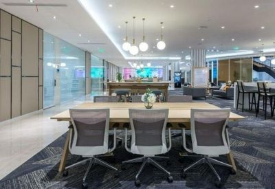 Bright open-plan coworking space with long wooden tables and designer pendant lights.