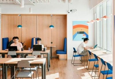 Meeting area featuring wooden desks, blue chairs, and semi-private wood-paneled booths.