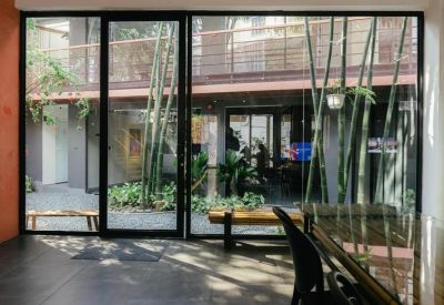 Modern glass-walled meeting room overlooking an internal courtyard with tall bamboo plants.