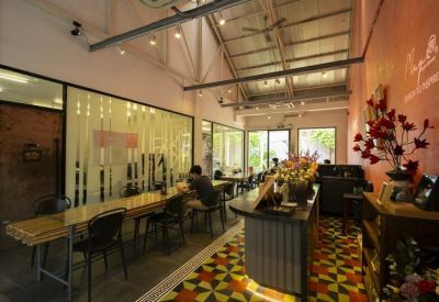 Spacious communal lounge with high ceilings, exposed beams, and decorative red flowers.