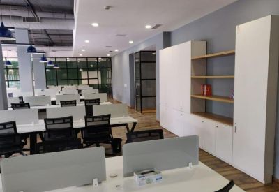 Open office area with white desks, black chairs, and tall white storage cabinets.