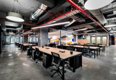 Open-plan workspace with long timber desks and industrial exposed ceiling.