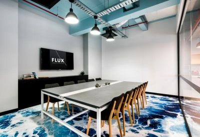 Contemporary meeting room with a large table, blue patterned carpet, and wall-mounted screen.