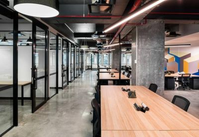 Perspective view of an open-plan office suite with long wooden workstations.