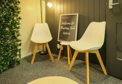 Cozy corner seating area with white chairs, a green feature wall, and a welcome sign.