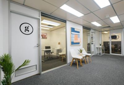 Bright office reception area with a branded door, white seating, and colorful artwork.