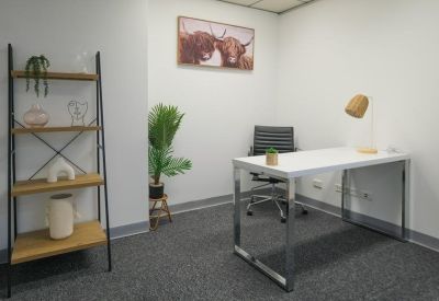Private office featuring a wooden ladder shelf, desk, and highland cow artwork.
