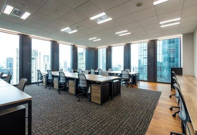 Open-plan office with grey desks and panoramic city views through large windows.