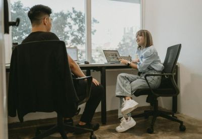 Private office suite with a desk, laptop, and large window overlooking trees.