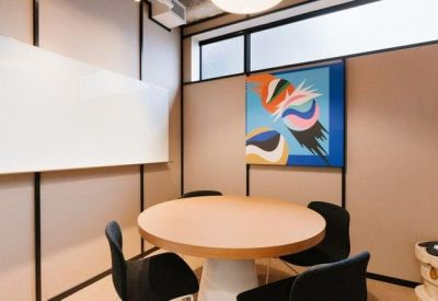 Private meeting room with a round wooden table, black chairs, and a colorful abstract painting.