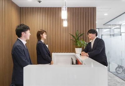 Bright reception area with a white desk and wood-slatted feature wall.